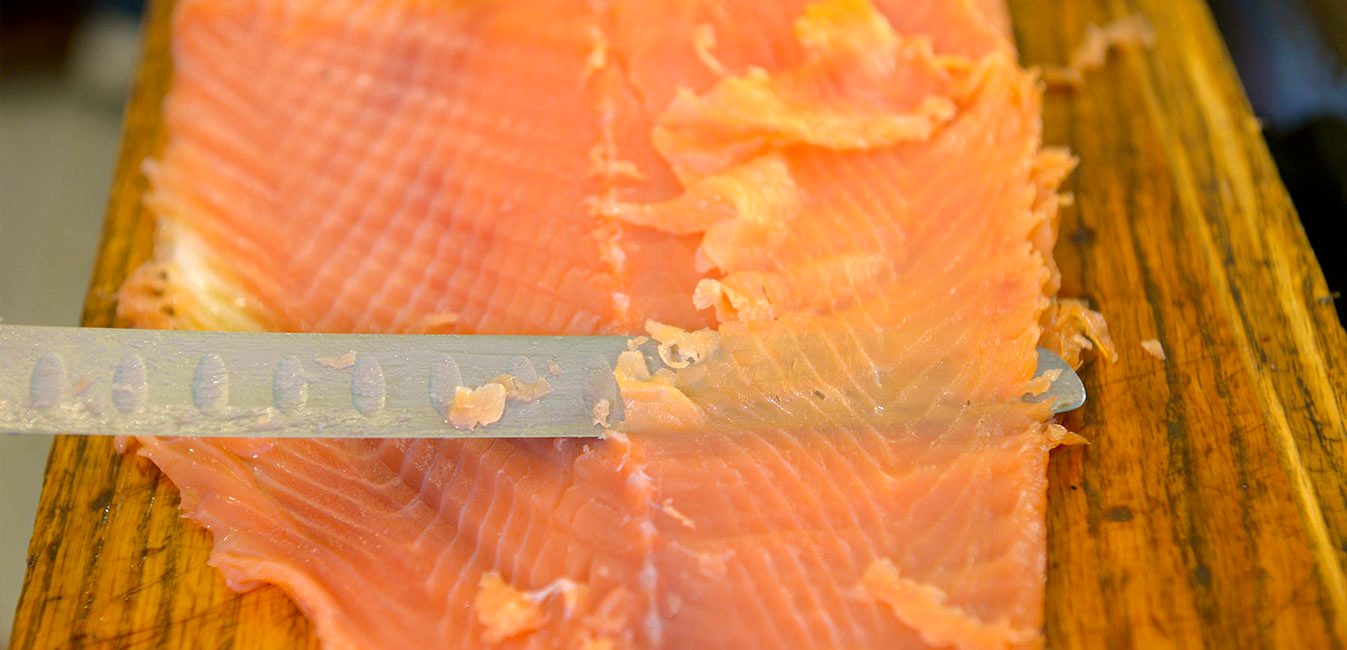 Hand-sliced smoked salmon on a cutting board